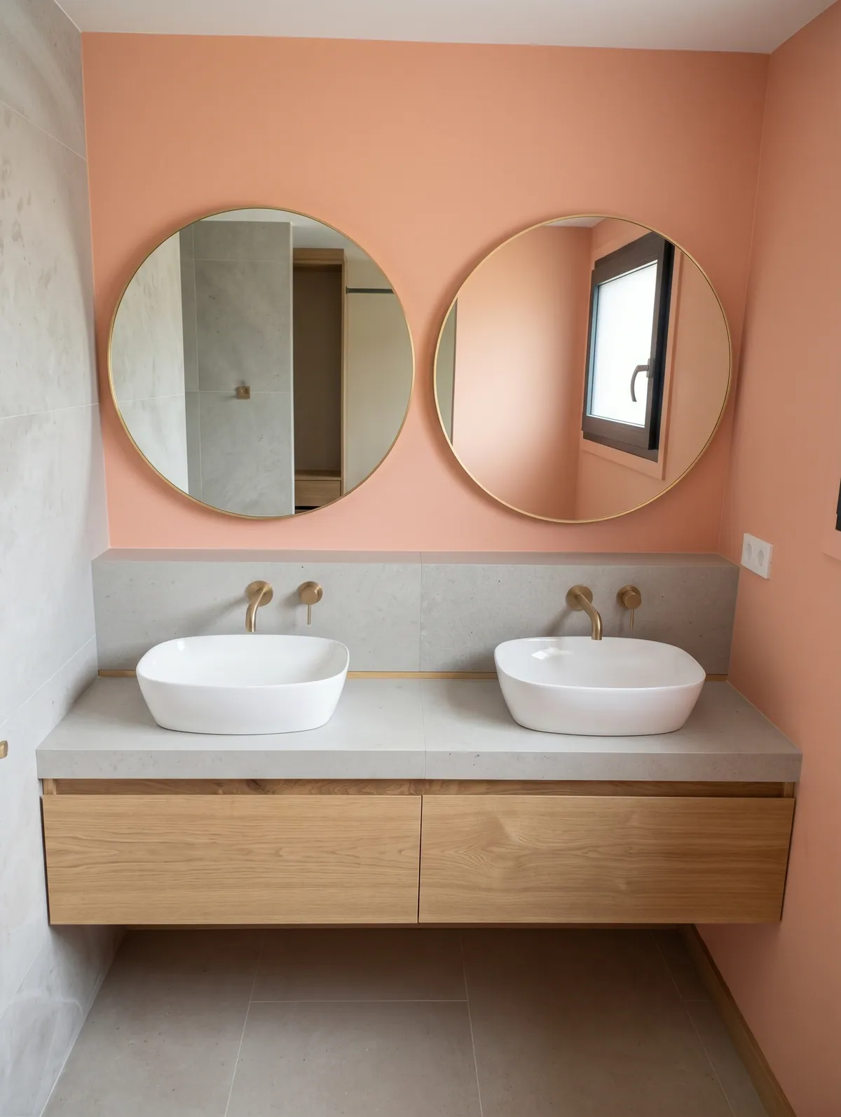 Meuble vasque en bois clair sous deux miroirs ronds, dans une salle de bain