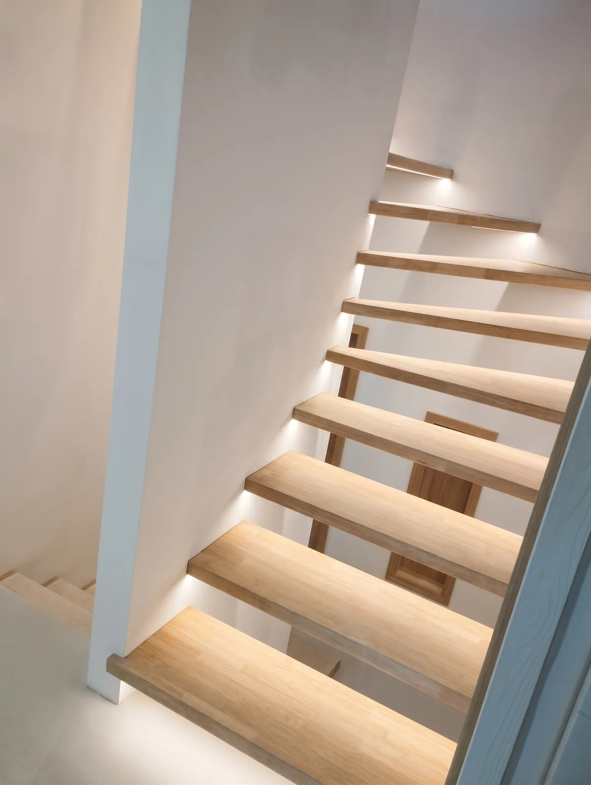 Escalier quart tournant à marches en bois, éclairées au ras du mur