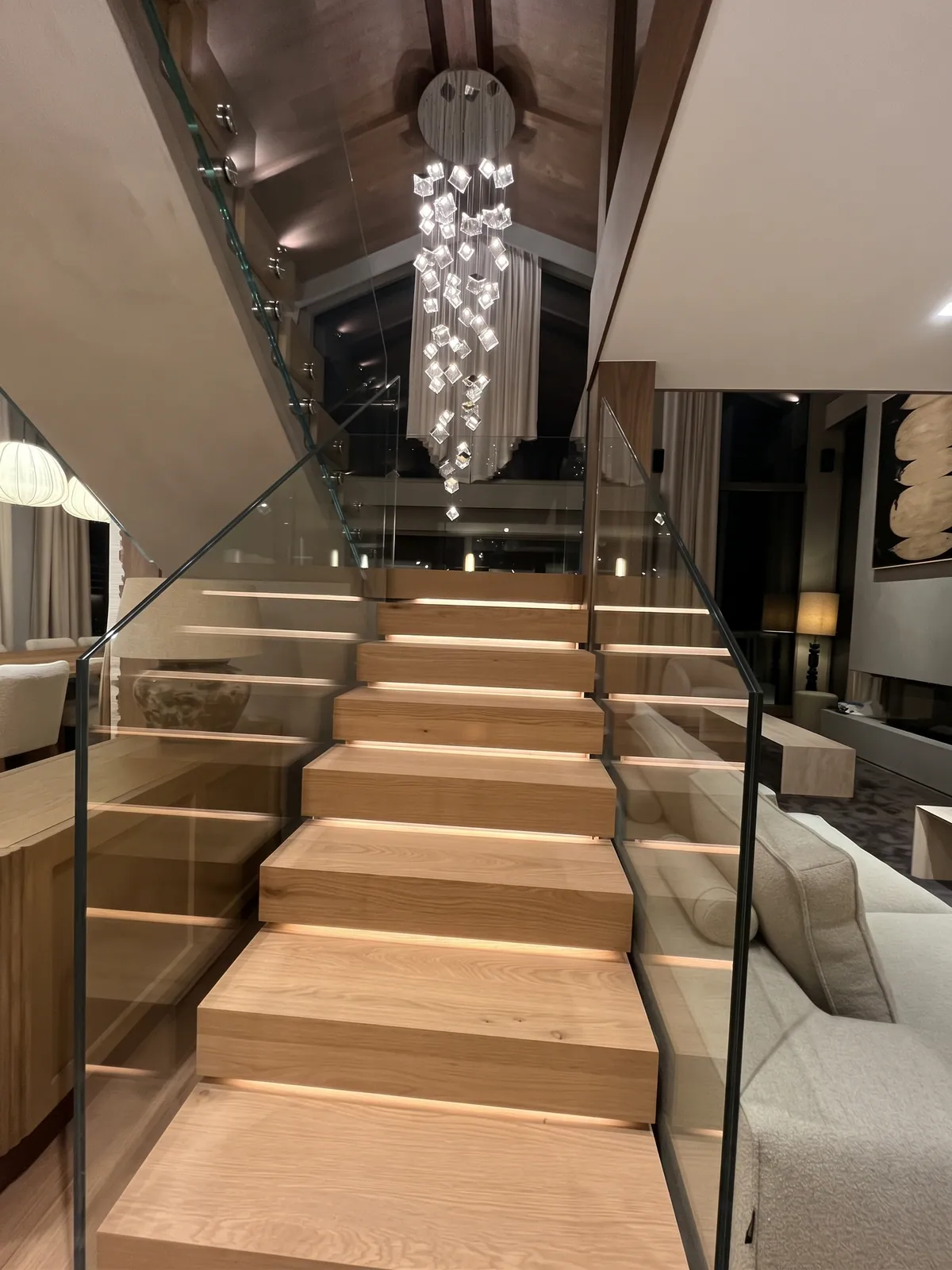 Grand escalier droit à marches en bois et garde-corps en verre, dans un séjour